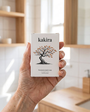 A hand holding the kakira box in a bright bathroom