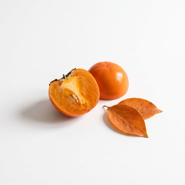 A persimmon cut in half with two leaves